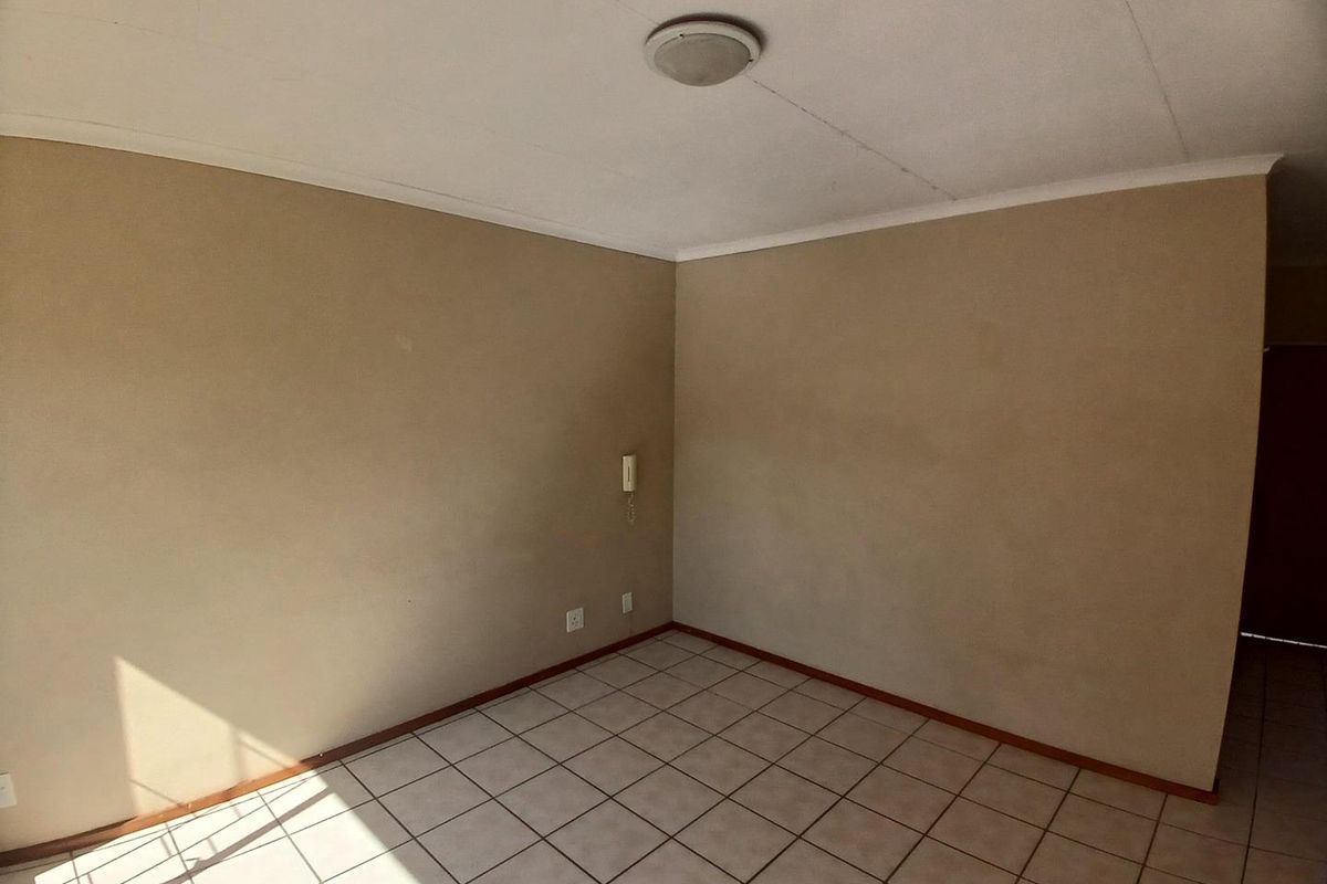 An empty living area featuring tiled flooring, a ceiling light fixture, and an intercom system, ready for personalization.
