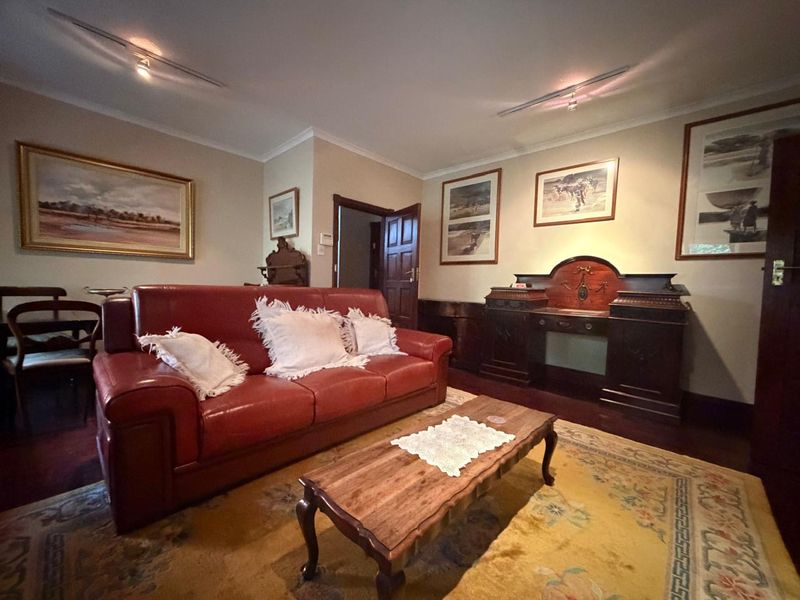 A traditional living room featuring timber door, coving, and track lighting, offering a classic aesthetic with potential for modern updates.