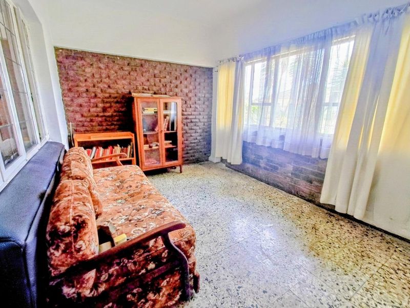 A living room featuring an exposed brick feature wall and traditional terrazzo flooring, offering a classic foundation for renovation.