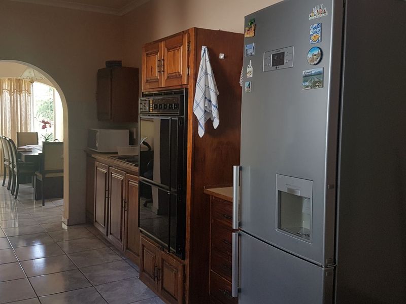 A functional kitchen featuring traditional wooden cabinetry, a built-in double oven, and tiled flooring, with an open archway leading into the adjacent dining area.