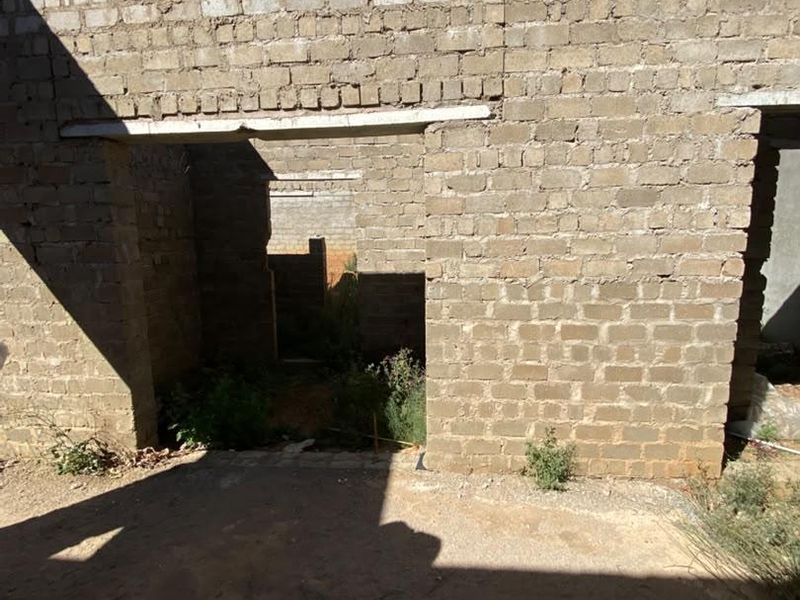 An unfinished exterior rear view of a property under construction, featuring exposed brick walls and concrete lintels.
