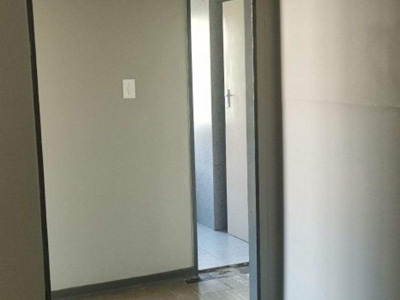 An empty hallway featuring an arched transition, ceiling fan, and vinyl tile flooring, leading into an adjacent room.