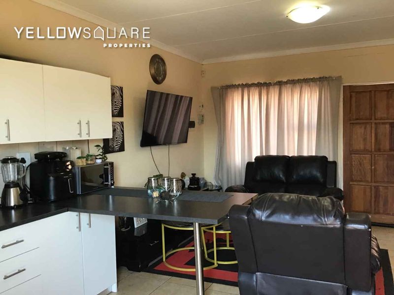 Open plan living area featuring a compact kitchen with built-in cabinetry and tiled flooring, providing a functional space for daily living.