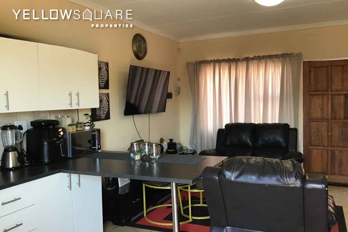 Open plan living area featuring a compact kitchen with built-in cabinetry and tiled flooring, providing a functional space for daily living.