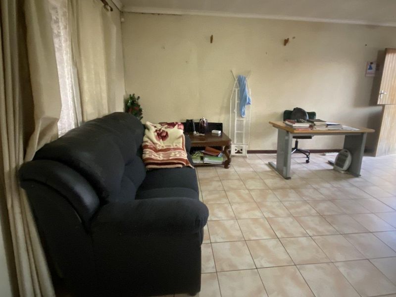 A living room area featuring ceramic floor tiles and curtain rails, showing signs of wear on the walls requiring maintenance and cosmetic updates.