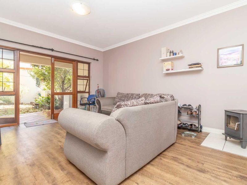 Living room featuring laminate flooring, a wood-burning stove on a tiled hearth, and sliding glass doors providing access to the outdoor area.