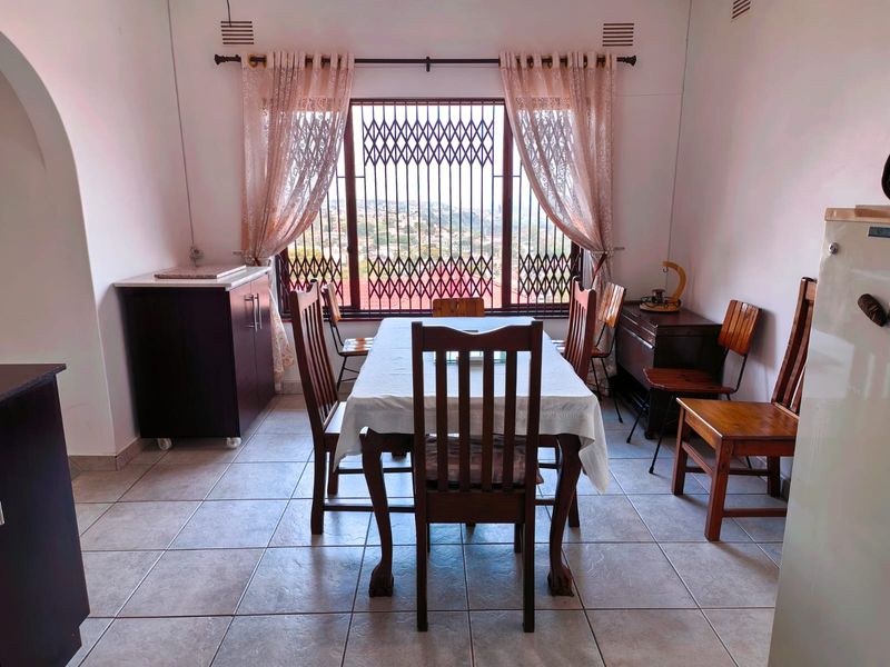 A dining room featuring tiled flooring and a large window with a security gate, offering a view of the surrounding area.