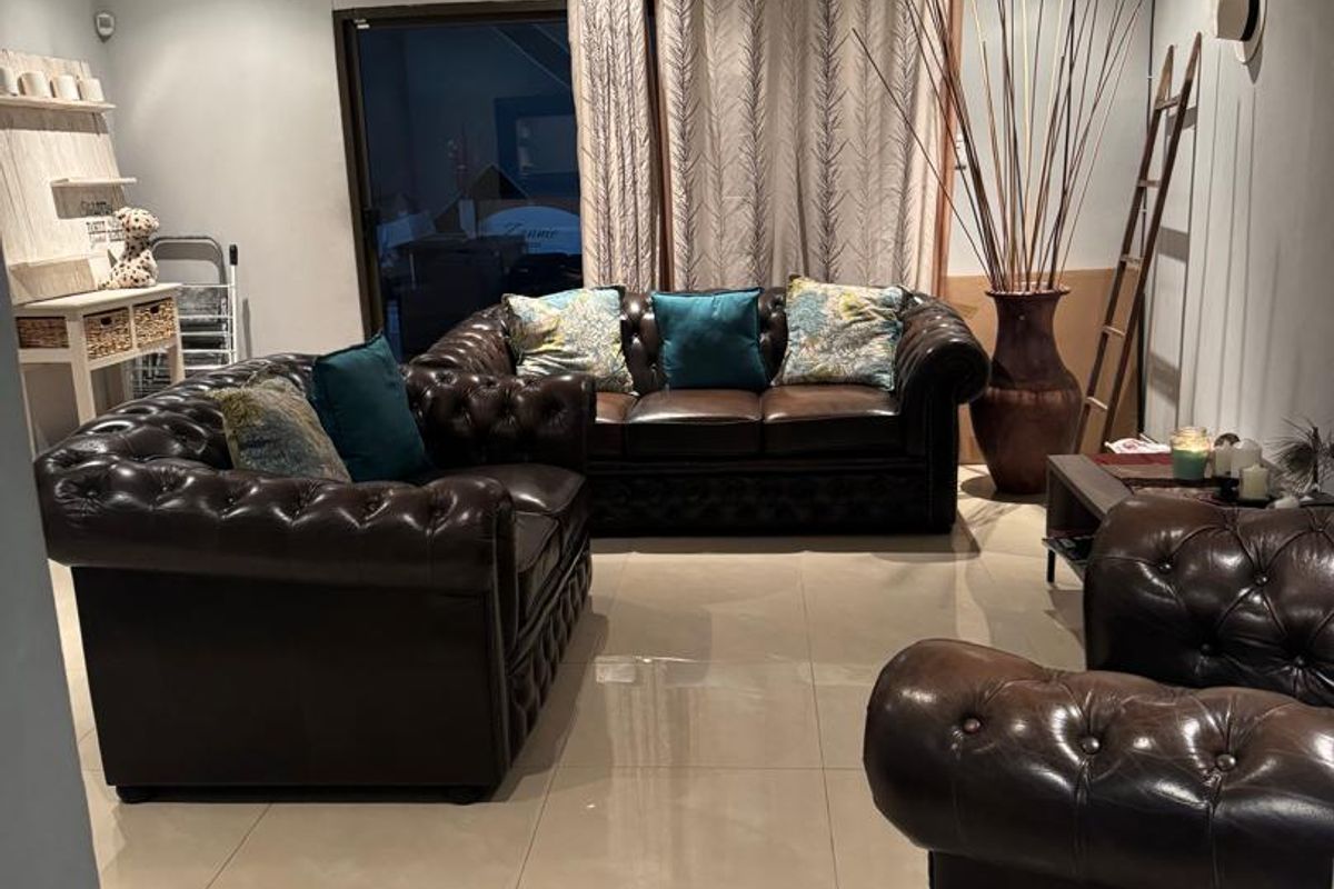 A well-maintained living room featuring polished porcelain floor tiles, recessed downlighting, and a sliding glass door providing access to the exterior.