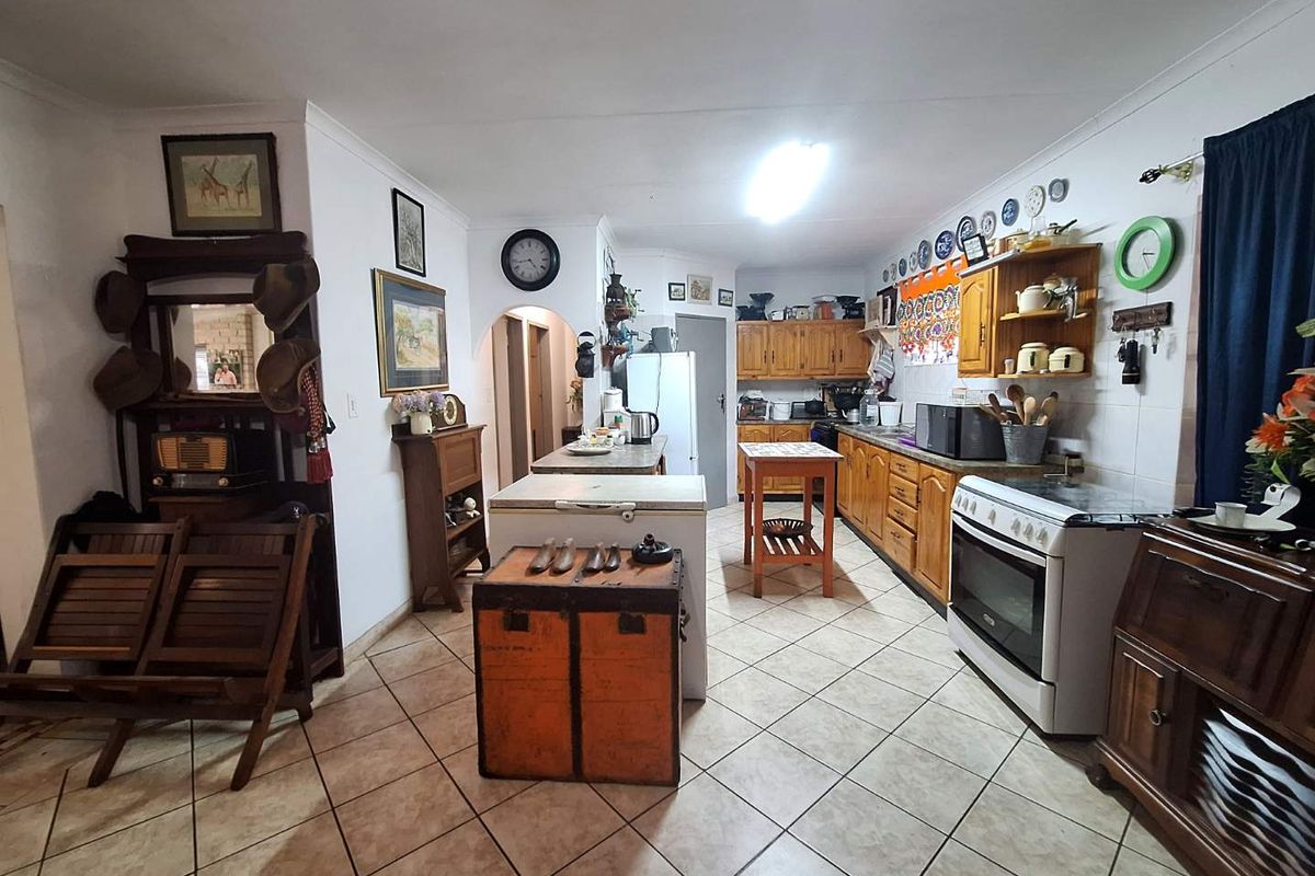 A functional kitchen featuring wooden cabinetry, tiled flooring, and a freestanding stove, offering a traditional layout with ample storage space.