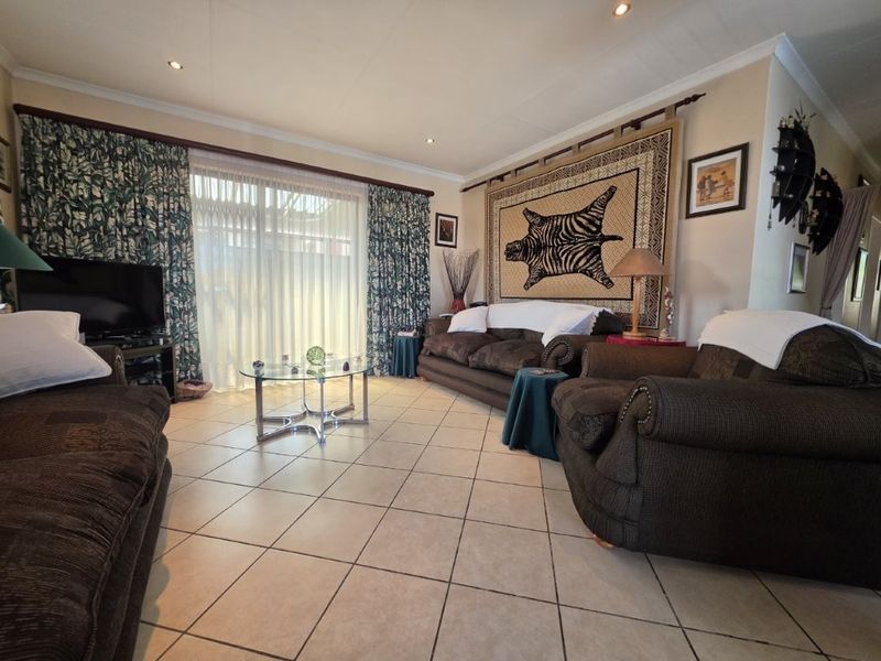 A spacious living room featuring tiled flooring, recessed downlighting, and a large sliding glass door providing access to the exterior.
