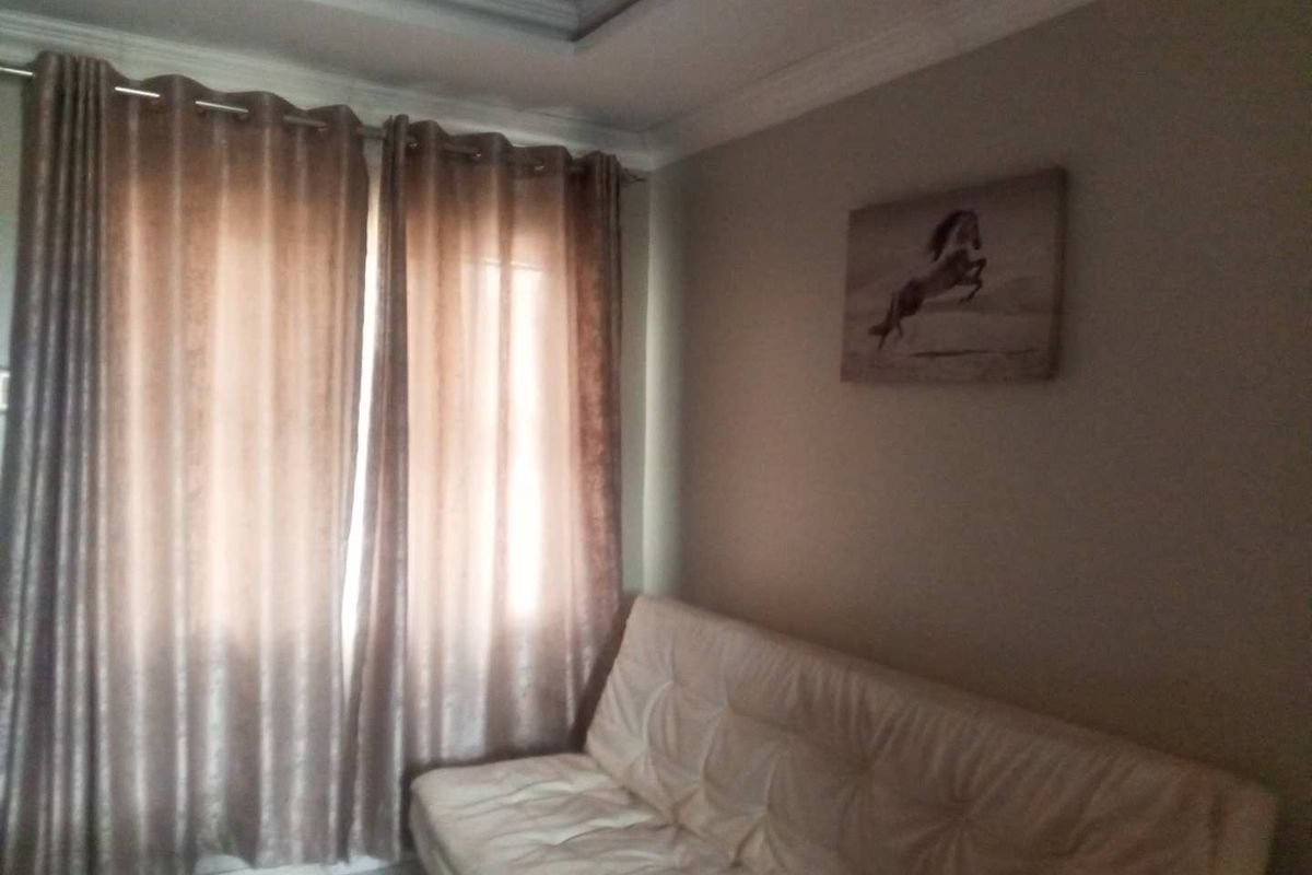 A living room area featuring crown molding and floor-to-ceiling curtains.
