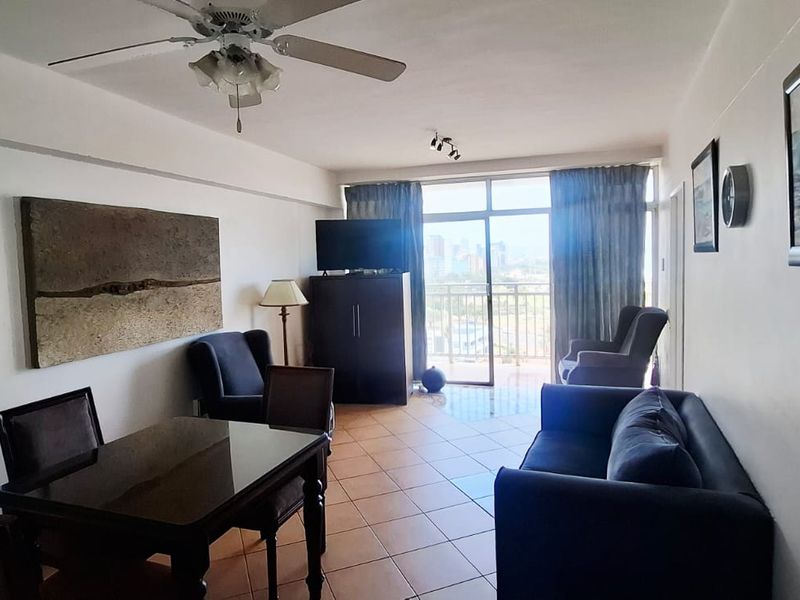 Open plan living and dining area featuring tiled flooring, a ceiling fan, and large sliding glass doors leading to a balcony.