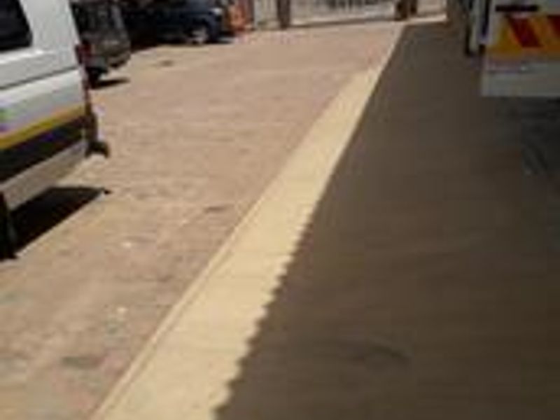 An exterior view of the industrial property showing a concrete driveway and covered walkway area.