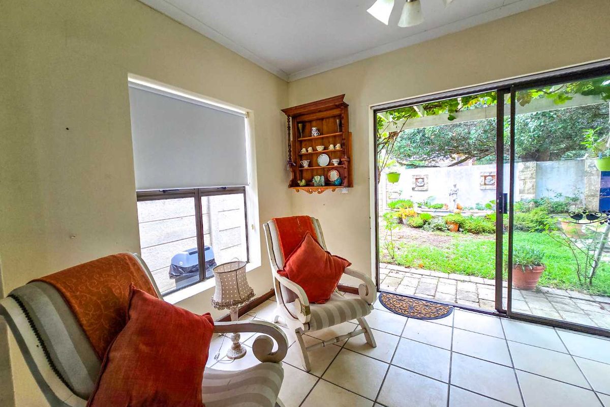 A sunlit living room featuring tiled flooring and large sliding glass doors that provide direct access to the rear garden patio.