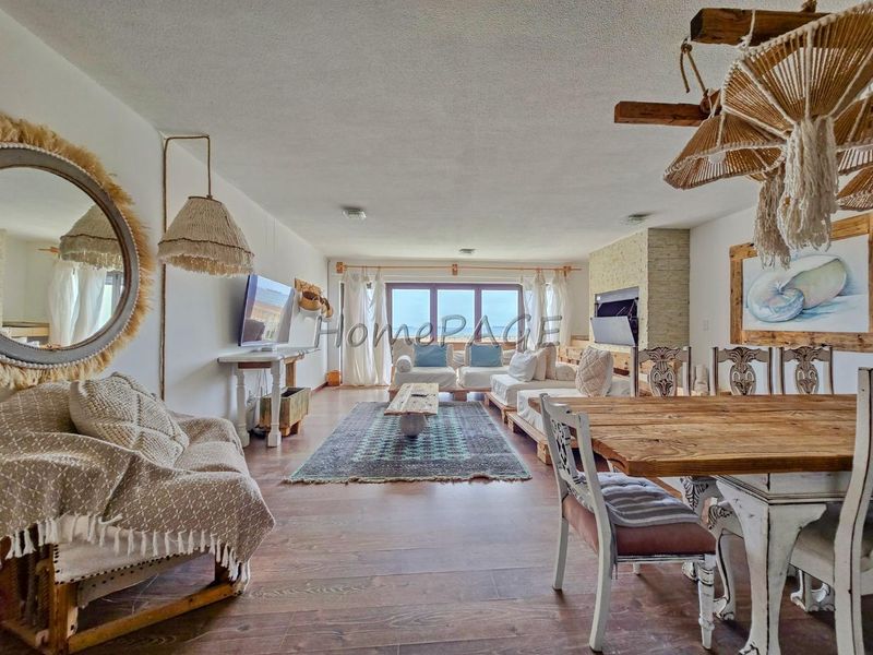 Spacious open-plan living and dining area featuring a stone fireplace, large sliding glass doors, and warm laminate flooring with a bright, airy atmosphere.