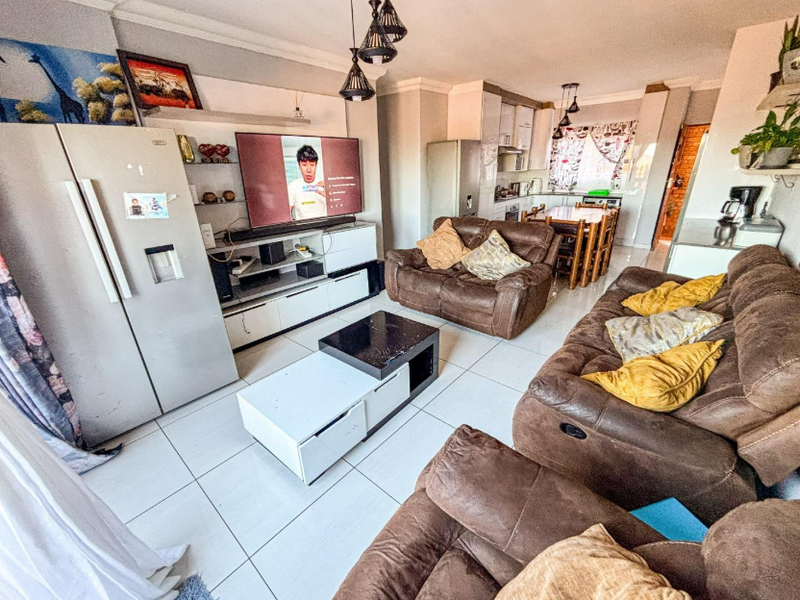 An open-plan living and kitchen area featuring tiled flooring, modern cabinetry, and pendant lighting, creating a functional and connected space for daily living.