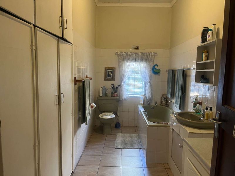 A dated bathroom featuring tiled walls and floors, built-in storage cabinetry, a bathtub, and a vanity basin.