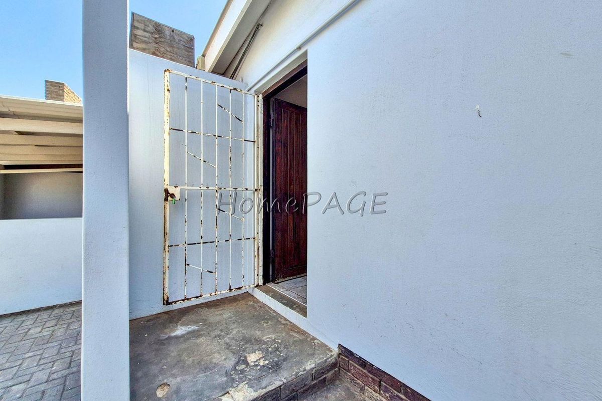 Exterior view of a side entrance featuring a security gate and concrete step leading into the property.