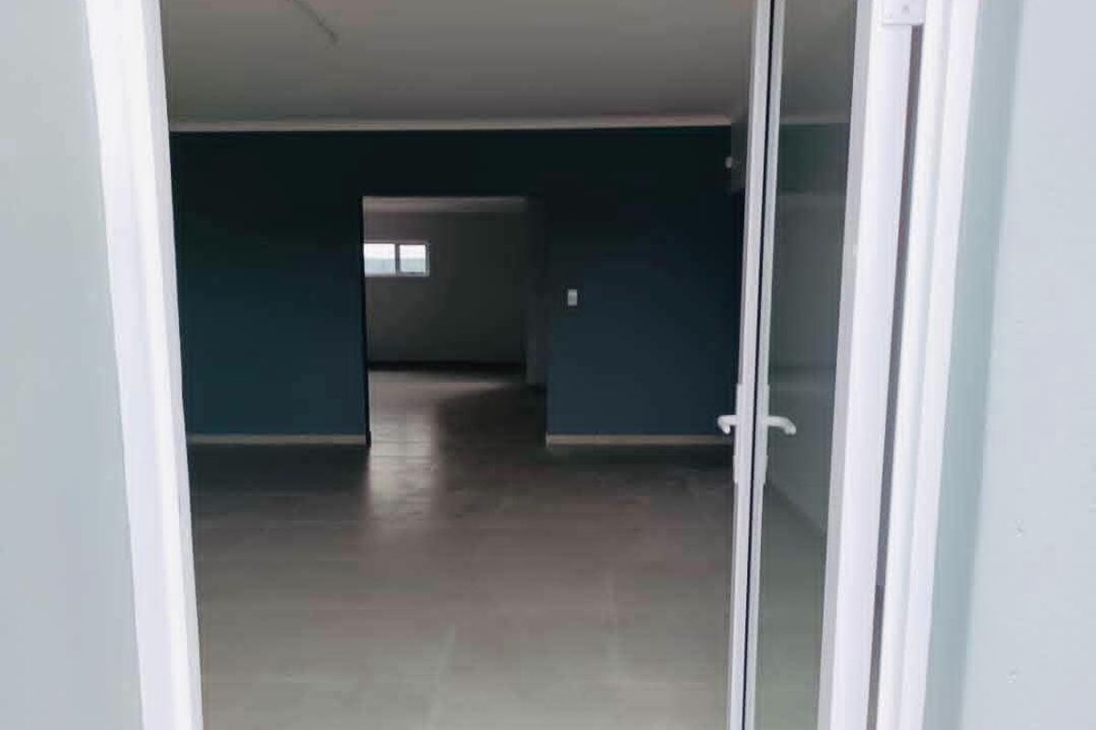 An empty, open-plan living area featuring tiled flooring and a sliding glass door entrance, finished with dark blue accent walls.