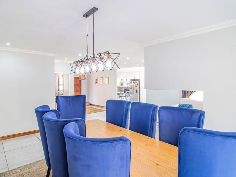 Spacious open-plan dining area featuring modern pendant lighting, neutral tiled flooring, and seamless flow into the adjacent kitchen space.