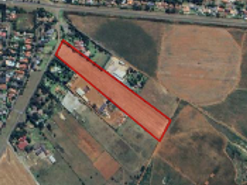 Aerial view of a rectangular plot of vacant agricultural land with a red boundary outline indicating the property perimeter.