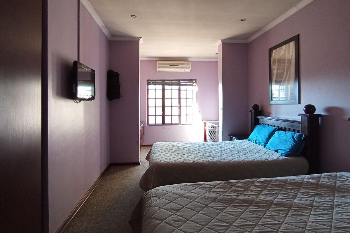Spacious bedroom featuring built-in cupboards, wall-mounted air conditioning unit, and large window providing natural light.