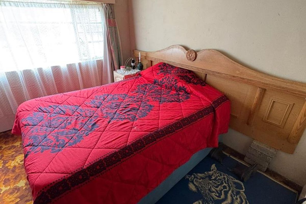 A bedroom featuring a built-in wooden headboard, large window with natural light, and carpeted flooring.