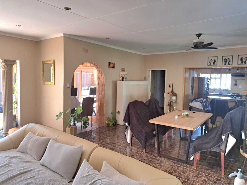 Spacious open-plan living and dining area featuring tiled flooring, a decorative stone archway, and integrated kitchen access.