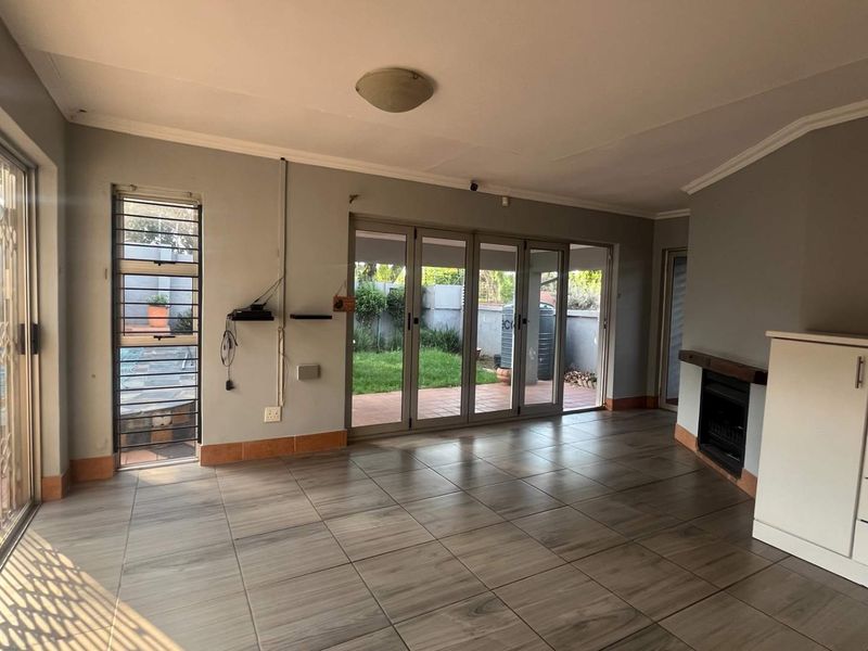 Spacious living area featuring tiled floors, a built-in fireplace, and large folding glass doors providing seamless access to the outdoor patio and garden.