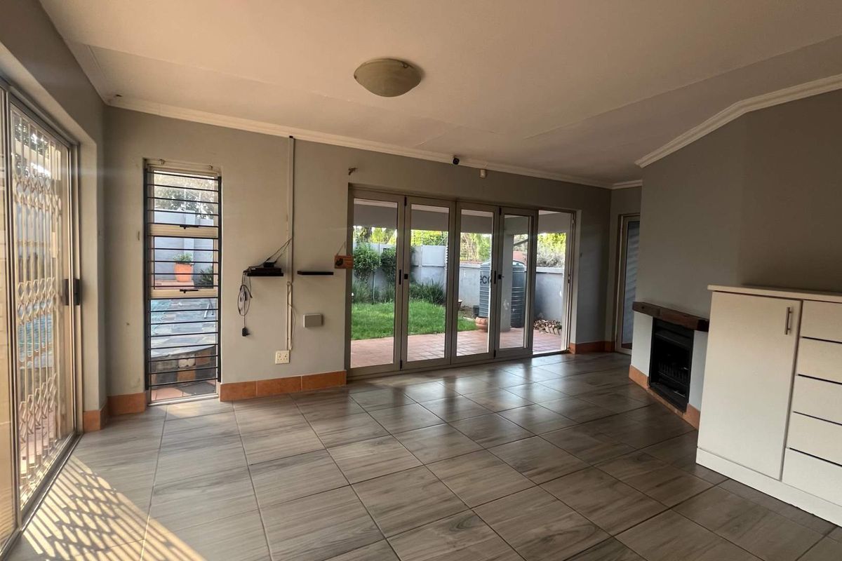 Spacious living area featuring tiled floors, a built-in fireplace, and large folding glass doors providing seamless access to the outdoor patio and garden.