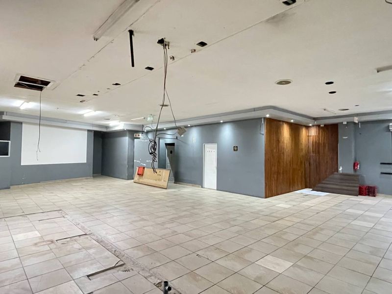 Spacious open-plan industrial interior featuring tiled flooring, a wood-paneled feature wall, and exposed ceiling infrastructure, offering a versatile layout for commercial use.