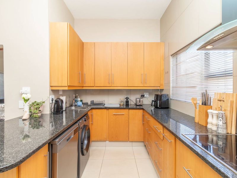 A functional kitchen featuring wooden cabinetry, granite countertops, integrated appliances, and tiled flooring, offering a clean and practical workspace.
