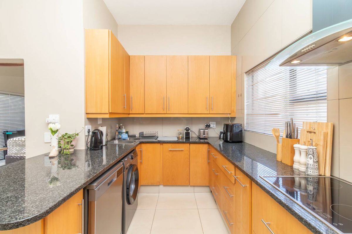 A functional kitchen featuring wooden cabinetry, granite countertops, integrated appliances, and tiled flooring, offering a clean and practical workspace.