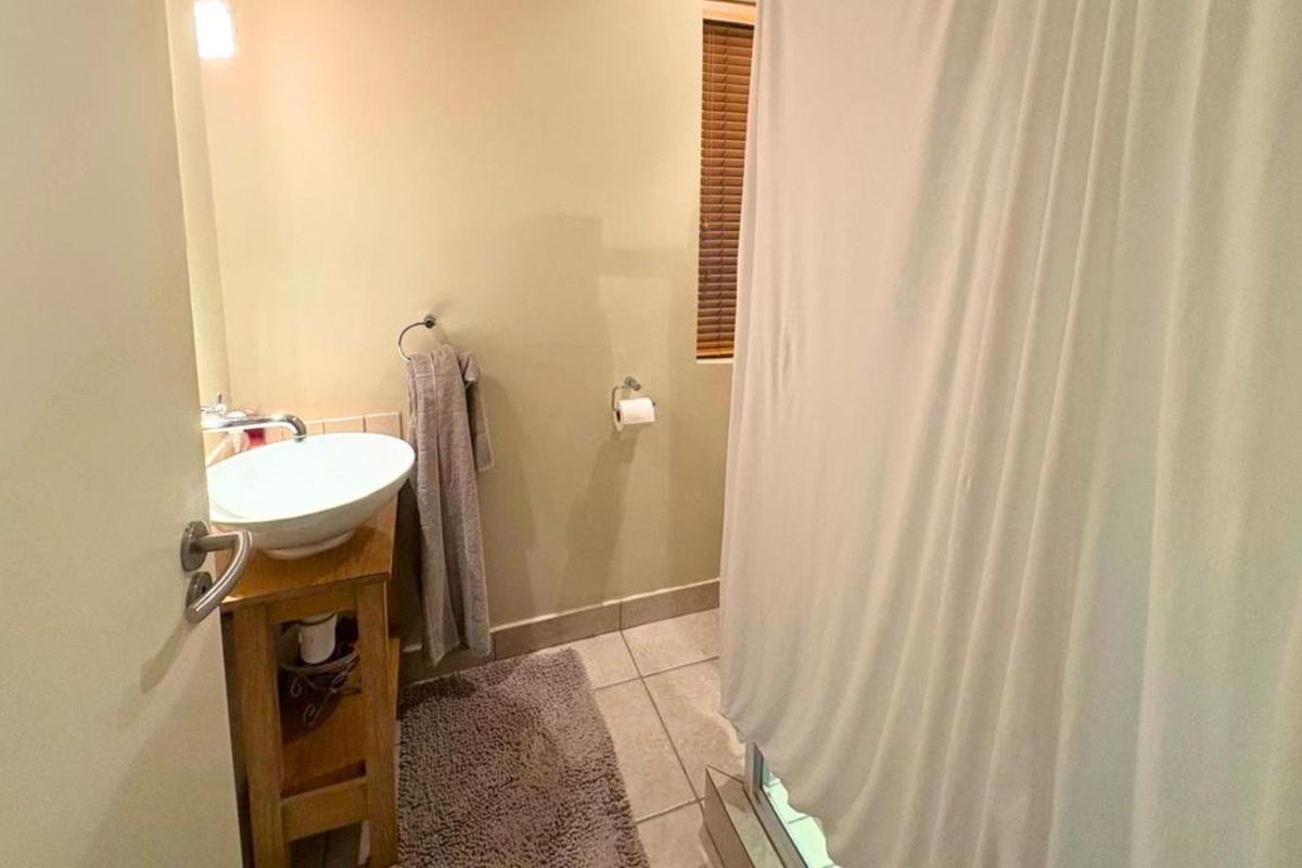 A functional bathroom featuring a vessel sink vanity, tiled flooring, and a shower enclosure with a curtain.