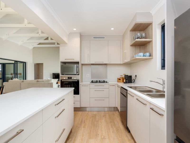 Modern open-plan kitchen featuring sleek cabinetry, stone countertops, integrated appliances, and high-quality finishes, seamlessly flowing into the adjacent living area.