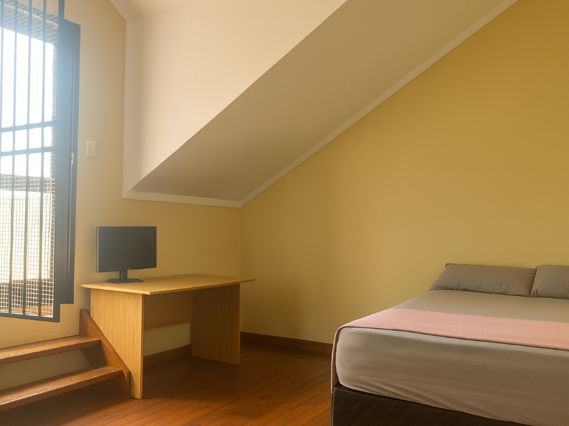 A bedroom featuring hardwood flooring, a sloped ceiling, and a window fitted with security bars, providing a functional living space.