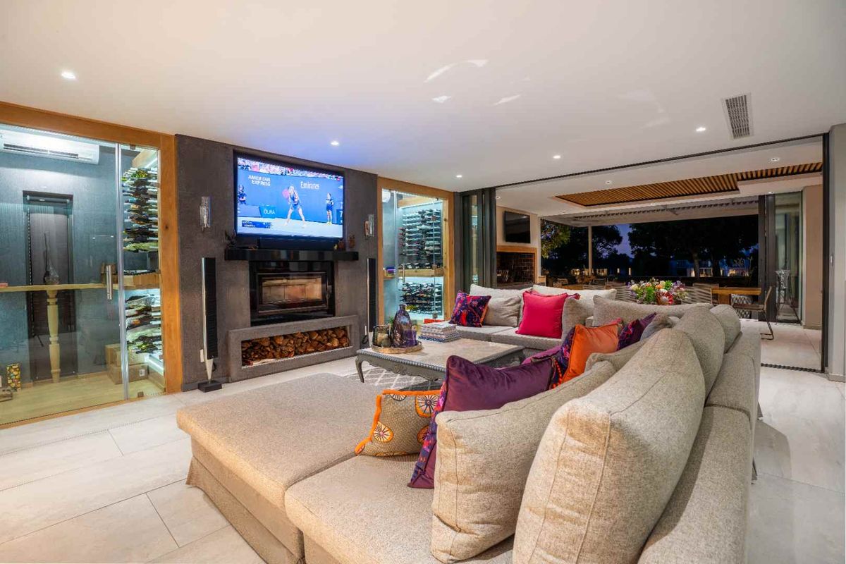 Spacious living room featuring a built-in fireplace, integrated glass wine cellar, and seamless flow to an outdoor patio area.