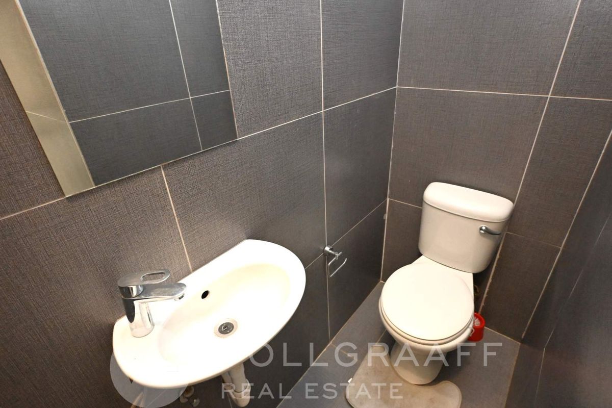 A compact guest bathroom featuring modern grey wall tiles, a wall-mounted basin with chrome tapware, and a standard toilet.