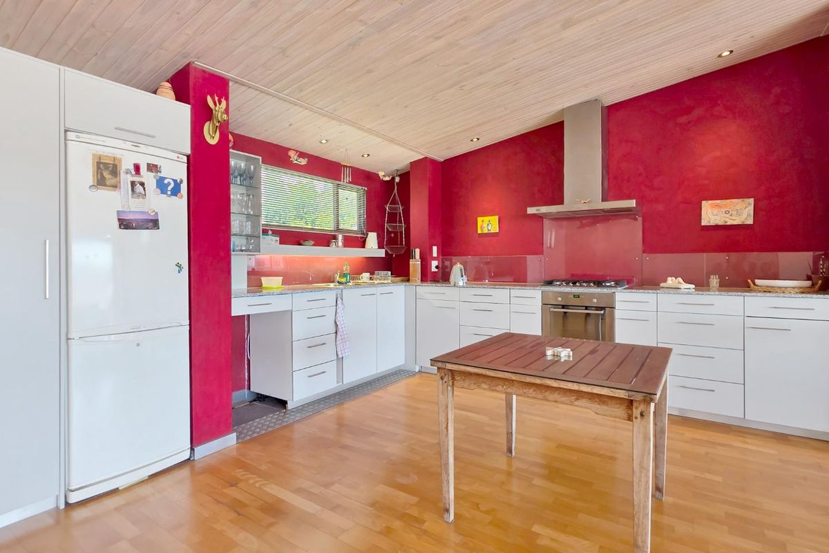 A functional kitchen featuring white cabinetry, a stainless steel extractor fan, gas hob, glass splashback, timber ceiling, and hardwood flooring.