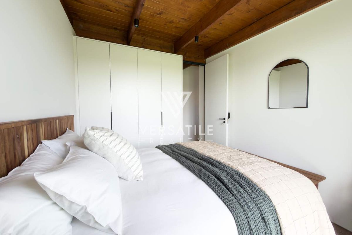 A well-maintained bedroom featuring exposed timber beam ceilings and built-in floor-to-ceiling cabinetry.