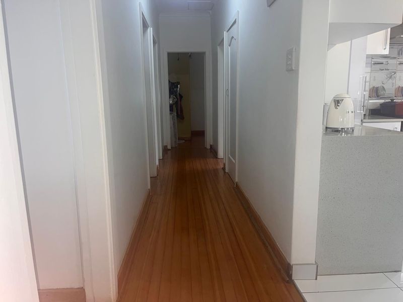 A clean, functional hallway featuring polished timber flooring and multiple internal door access points, connecting the living area to the rest of the home.