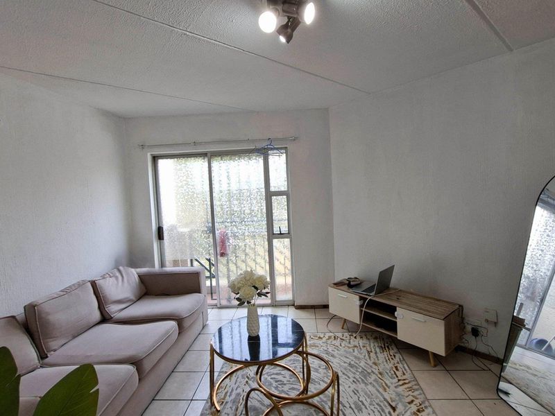 A living room featuring tiled flooring and a sliding glass door providing access to an outdoor area.