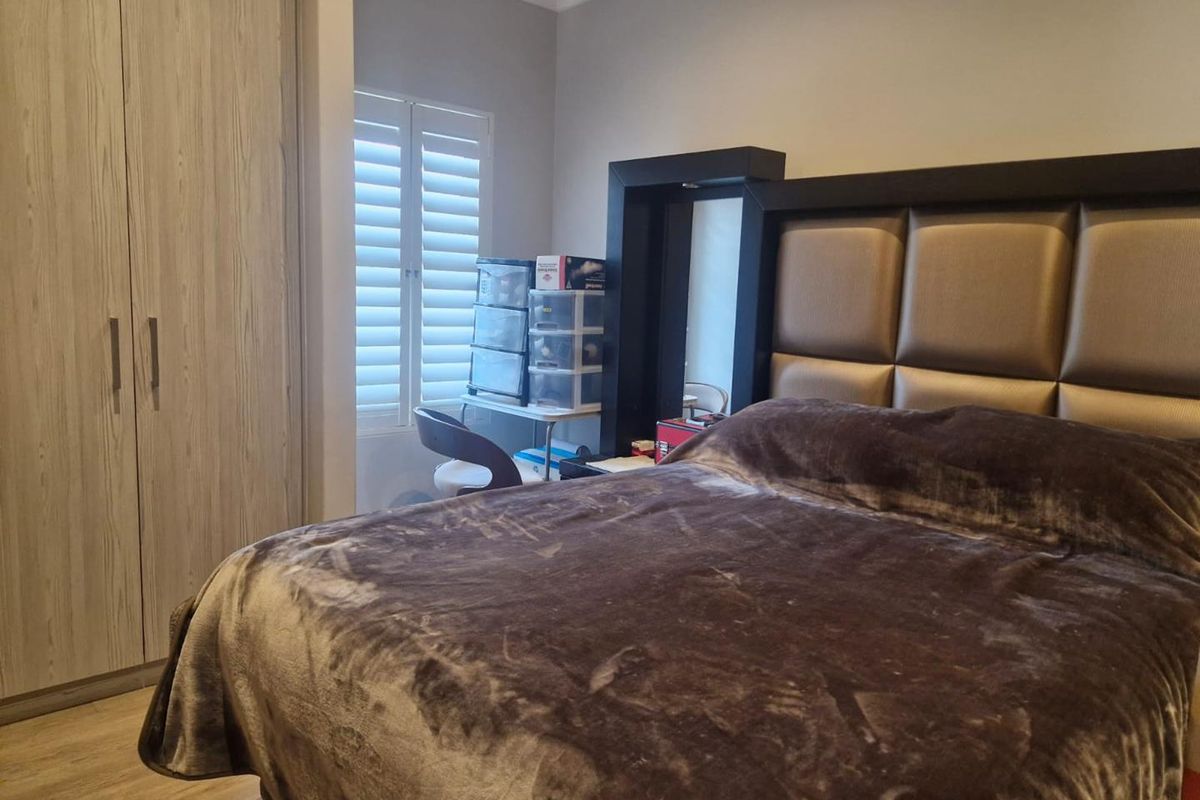 A well-maintained bedroom featuring built-in wooden cabinetry and plantation-style window shutters, providing a clean and functional living space.