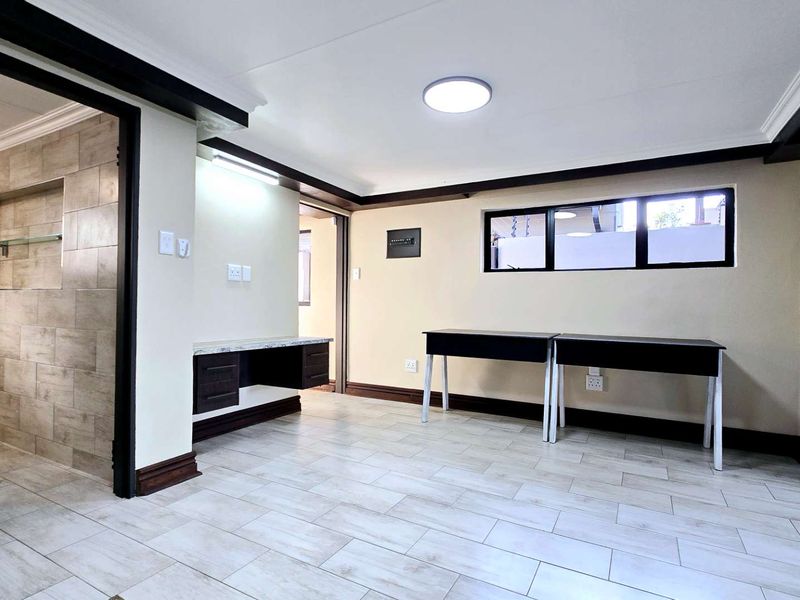 A clean, modern office space featuring tiled flooring, built-in cabinetry, and neutral wall finishes, providing a versatile area for work or study.