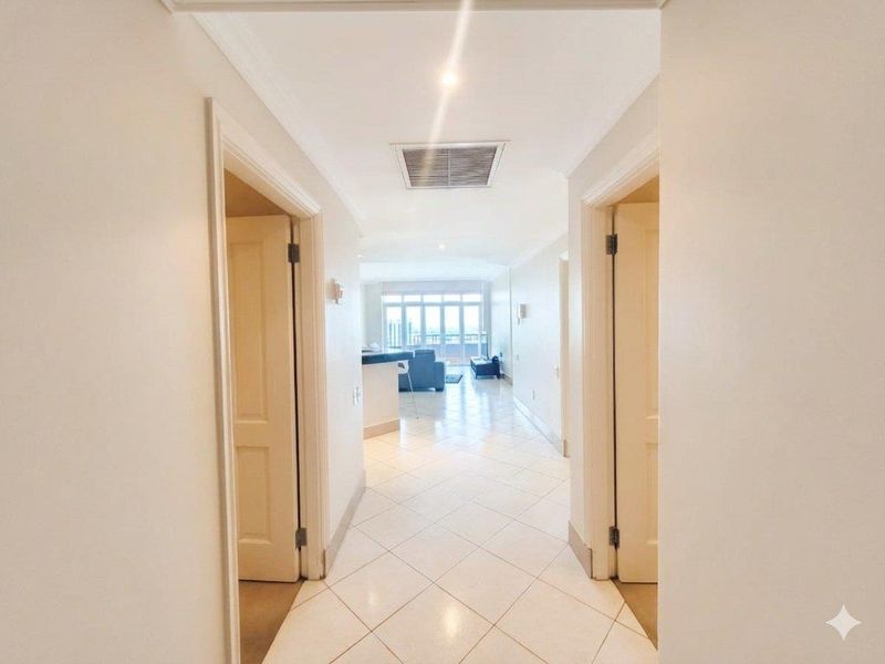 A bright, tiled hallway leading from the entrance into an open-plan living area with natural light and neutral finishes.