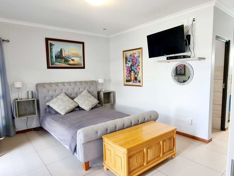 A well-maintained bedroom featuring neutral tiled flooring, recessed downlighting, and an integrated air conditioning unit.