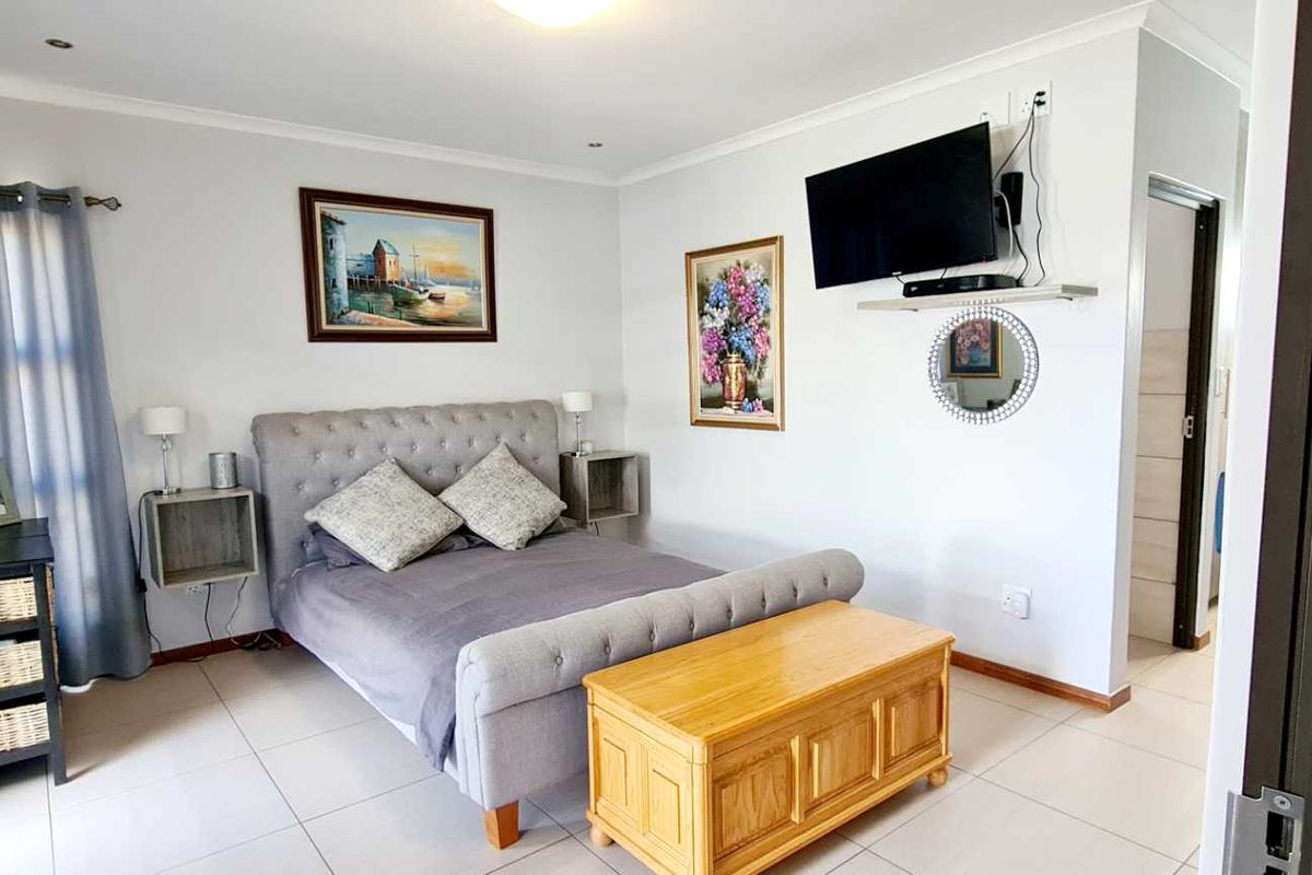 A well-maintained bedroom featuring neutral tiled flooring, recessed downlighting, and an integrated air conditioning unit.
