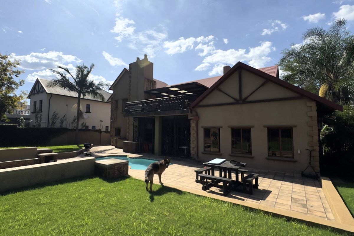 Rear view of the property featuring a paved patio area, swimming pool, and landscaped garden space.