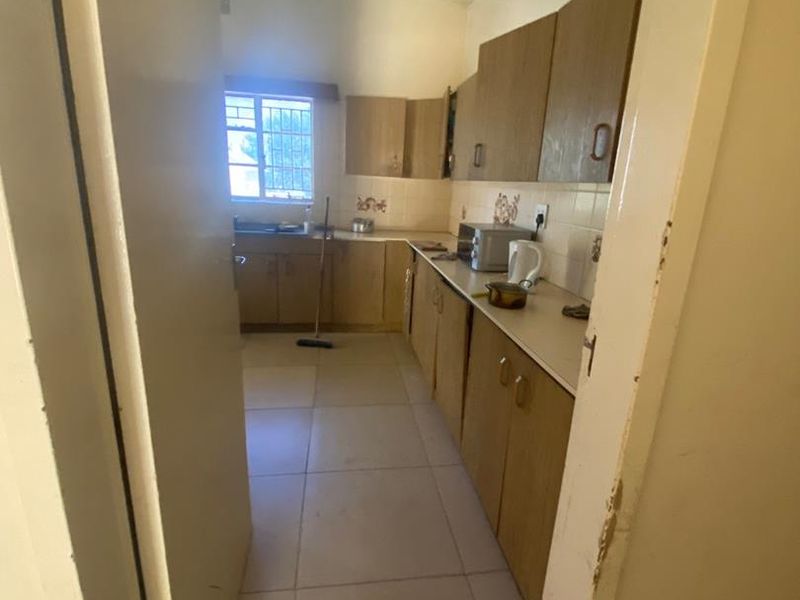 A functional kitchen featuring laminate cabinetry, tiled backsplash, and tiled flooring, offering a practical layout with a window for natural light.