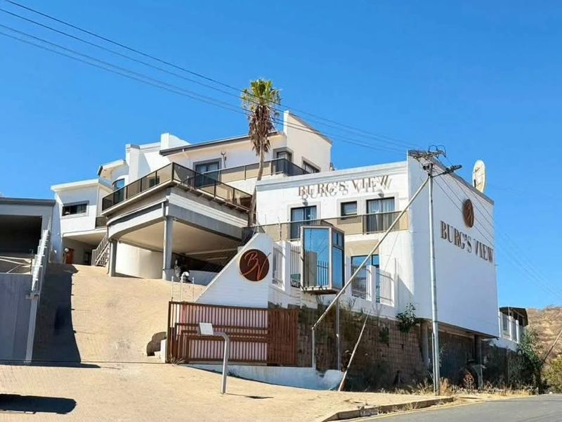 Front exterior view of Burg's View hotel property featuring a multi-level facade, glass elevator, and paved driveway access.